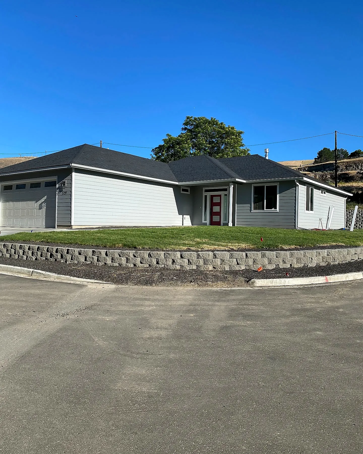 A refreshed residential front yard with a mowed lawn and stone retaining wall